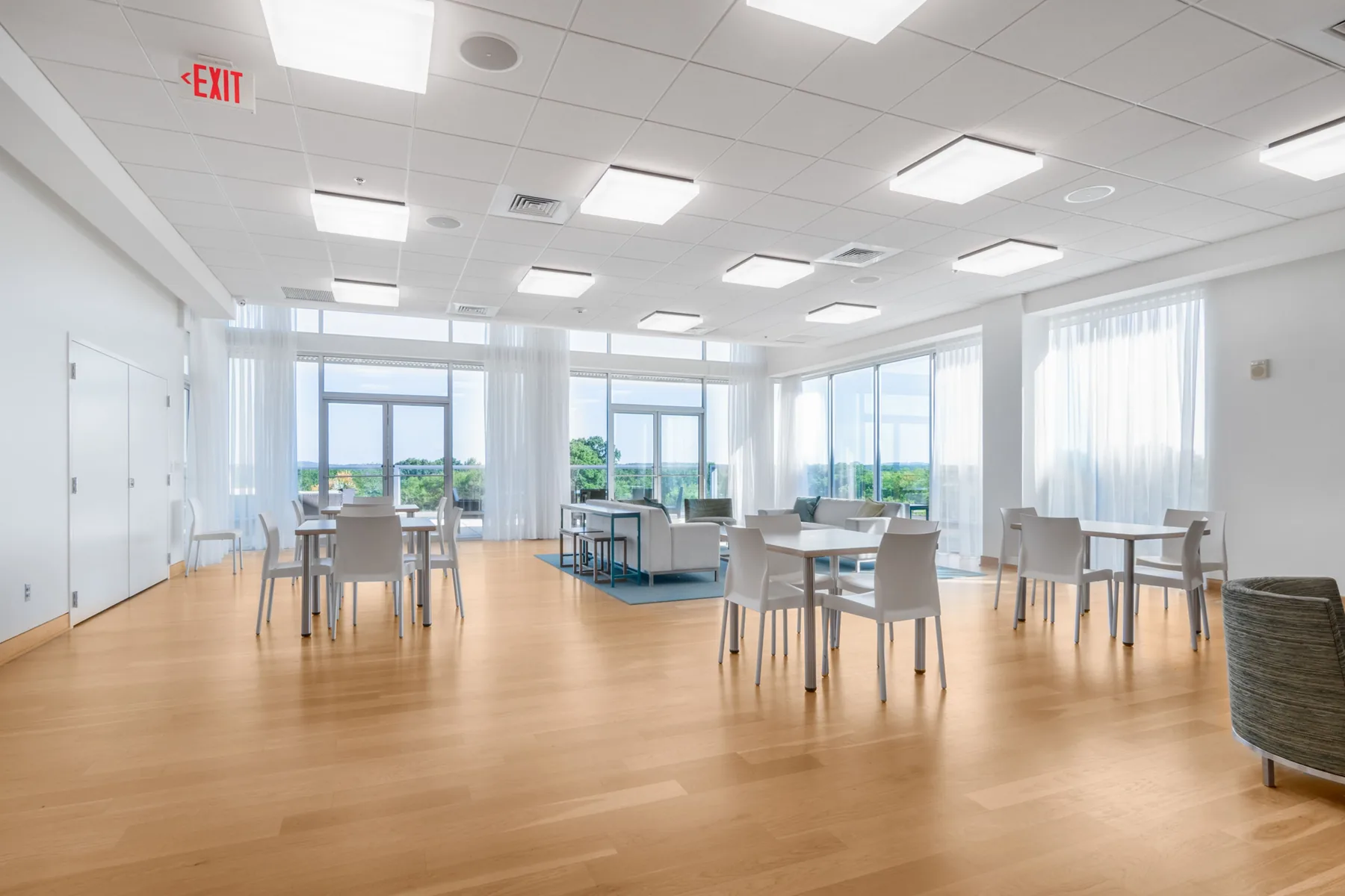 Bright community lounge with dining tables, seating, and open floor areas