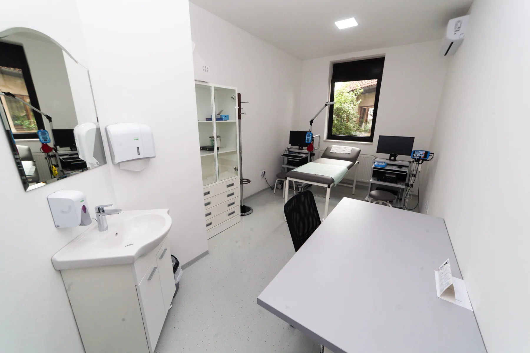 Bright, orderly medical examination room with sink and treatment table